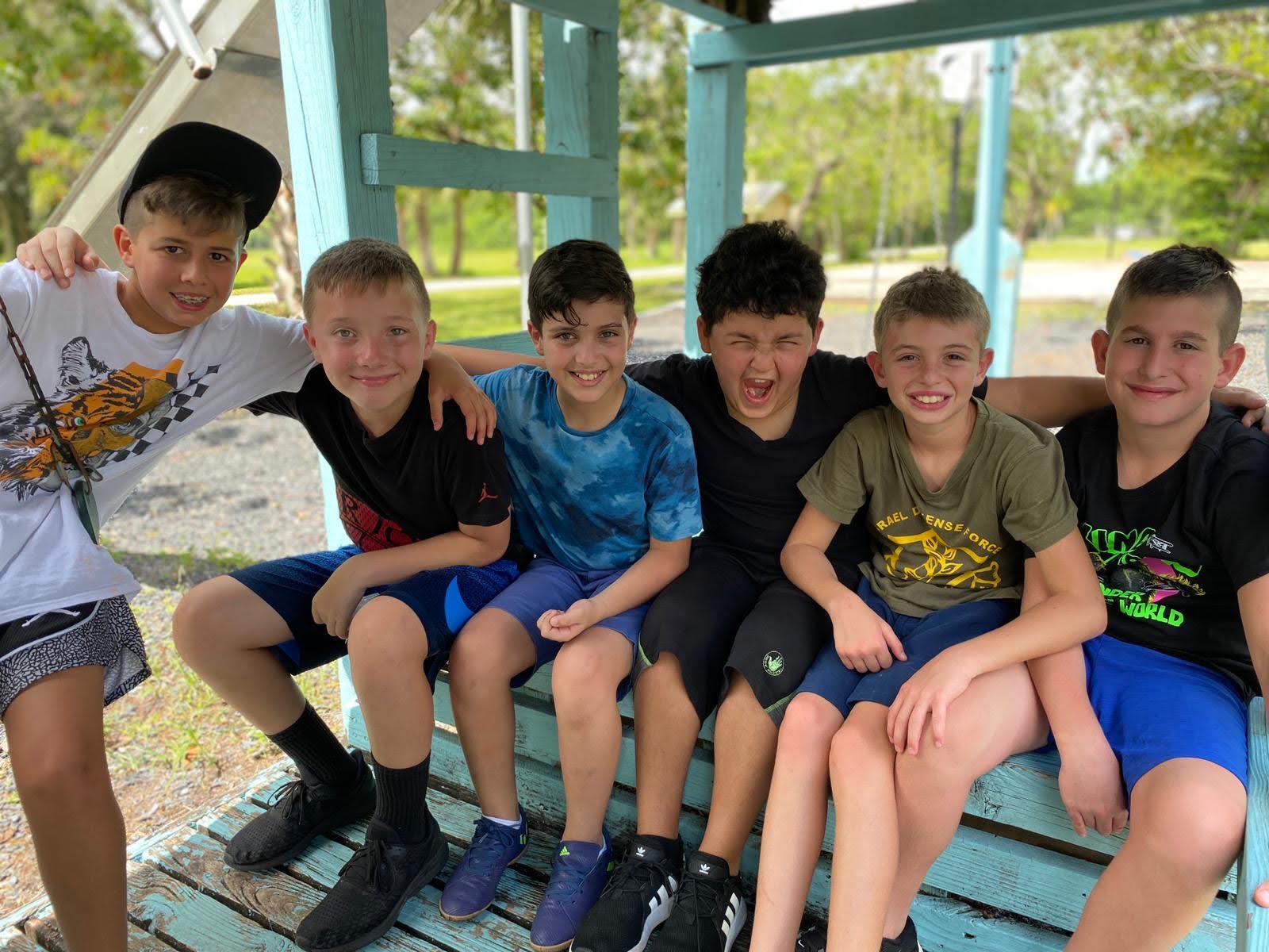 Six smiling Jewish boys arm in arm at CKids Gan Israel FL summer camp in Florida